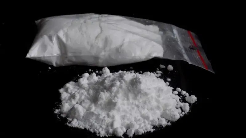 Cocaína en polvo dentro de una bolsita y volcada sobre una superficie negra